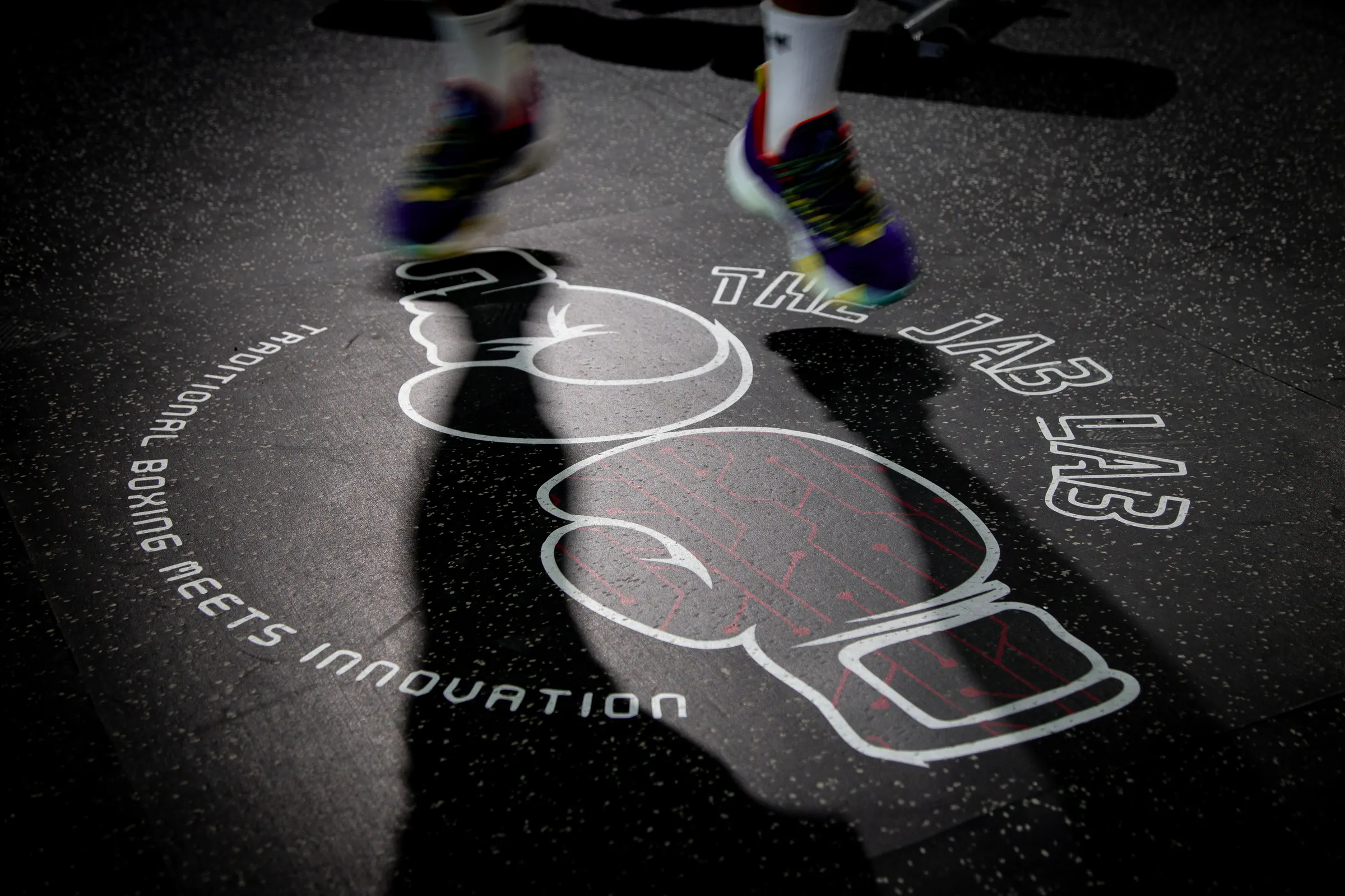 Light projection of boxing gloves and a club wordmark cast across a gym floor