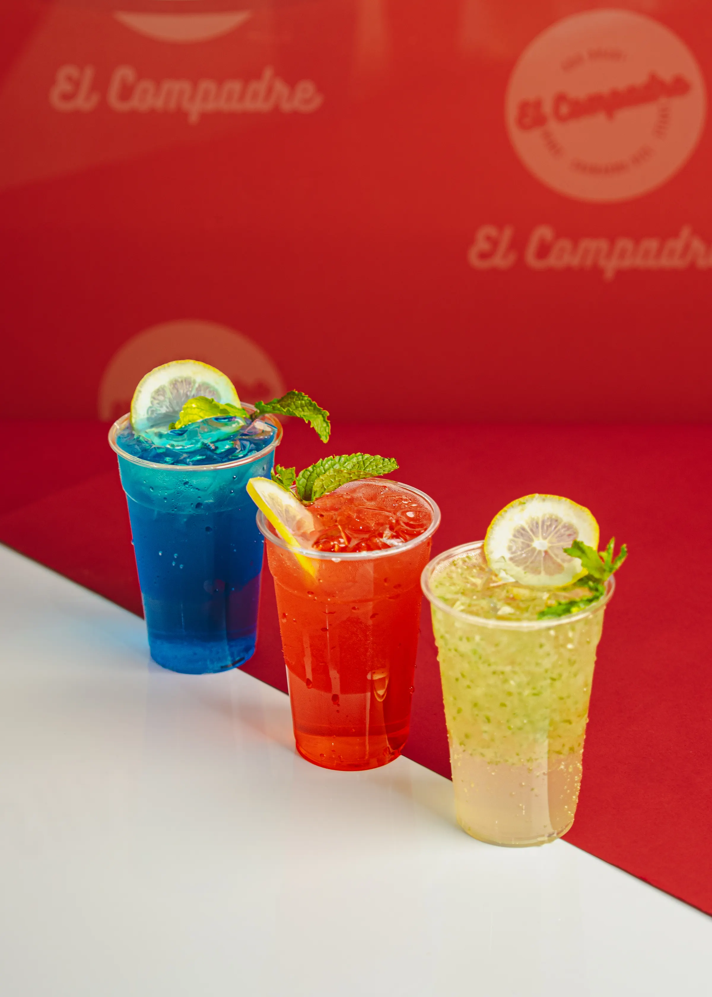 Three coloured iced drinks arranged in front of a branded restaurant backdrop