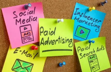 Coloured sticky notes pinned to a corkboard, each naming a marketing channel
